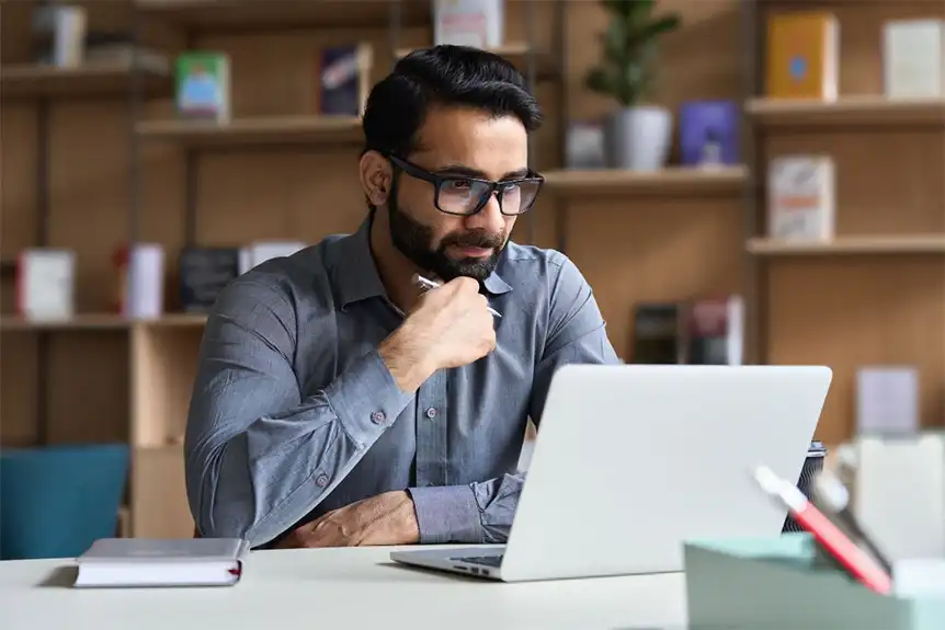 A man in his office staring intently at his laptop.